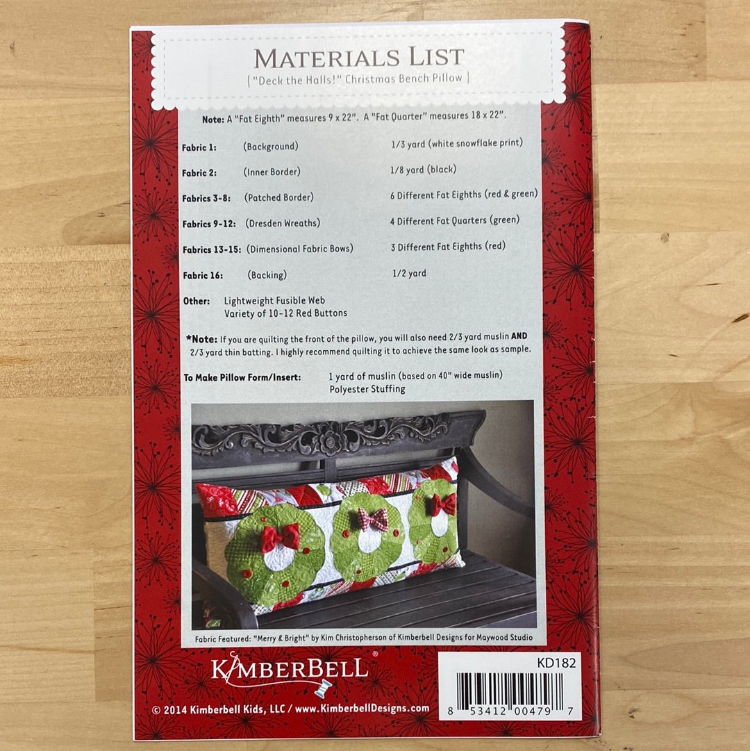 Get festive with our Deck the Halls! Bench Pillow Pattern (KD182) by Kimberbell. Adorned with appliqued wreaths and bows, this pattern includes a pieced border for added charm. Perfect for regular sewing machines, it's the perfect addition to your holiday decor. Photo shows the back cover of the package.
