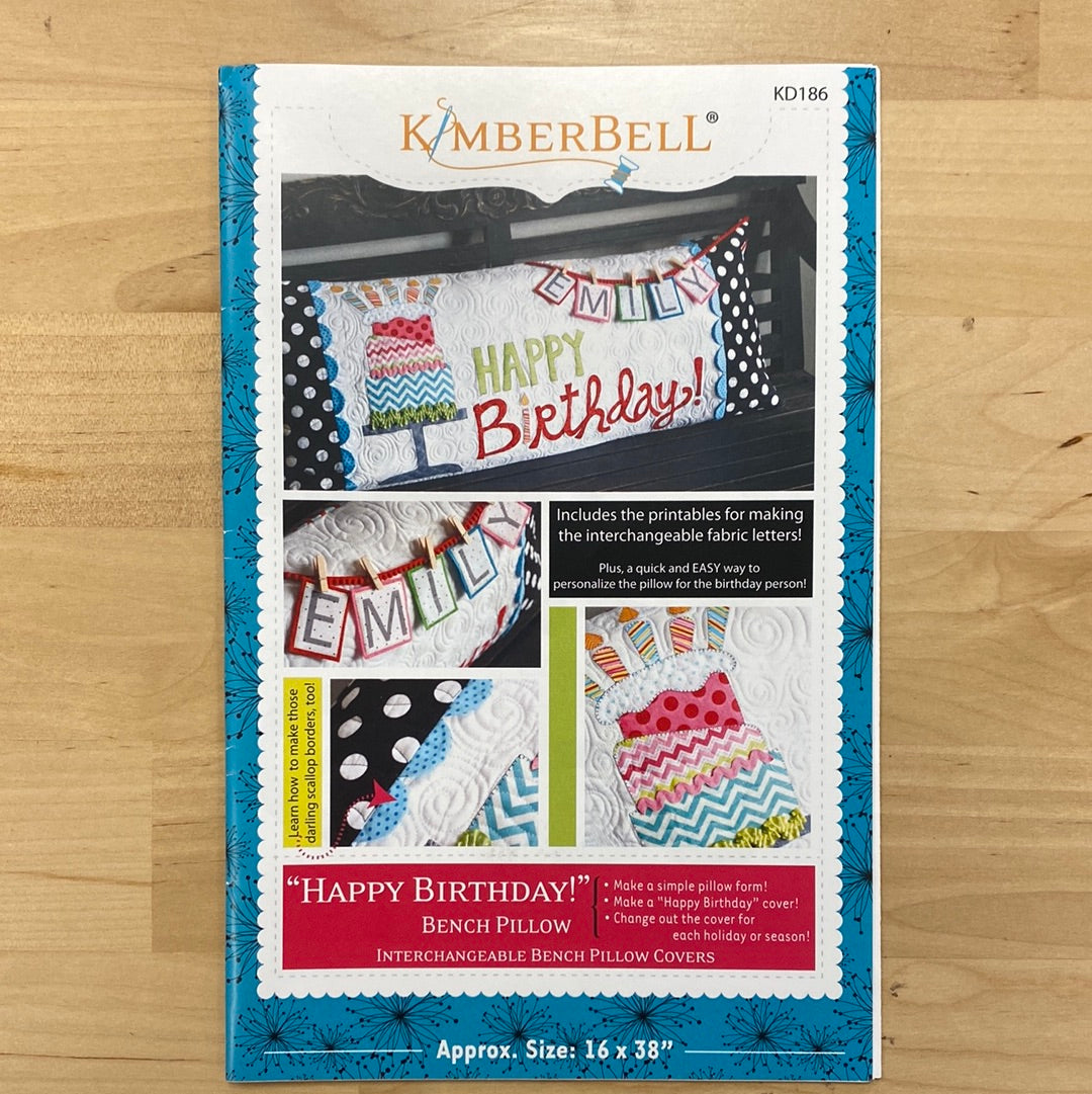 Celebrate in style with our Happy Birthday! Bench Pillow Pattern (KD186) by Kimberbell. This applique design works with a regular sewing machine and features a festive birthday cake on a cake stand complete with candles. The included interchangeable letters allow you to personalize the pillow with a name or sentimental message. Photo shows product cover.