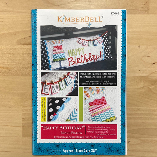 Celebrate in style with our Happy Birthday! Bench Pillow Pattern (KD186) by Kimberbell. This applique design works with a regular sewing machine and features a festive birthday cake on a cake stand complete with candles. The included interchangeable letters allow you to personalize the pillow with a name or sentimental message. Photo shows product cover.