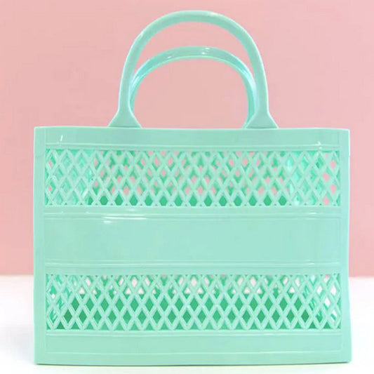 Made of durable PVC, this Mint Green tote is the jelly material from the 80's. Photo shows the tote against a pink and white background.