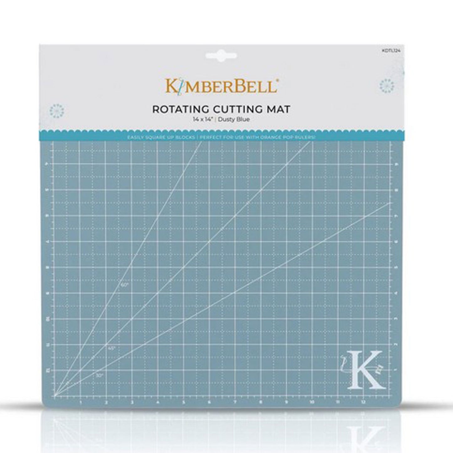 The Kimberbell Rotating Cutting Mat measures 13" x 13", and accommodates all sizes of the Orange Pop Ruler. The photo shows the front of the package, with the grid-lines visible on the blue-gray mat with Kimberbell K logo in lower right corner.