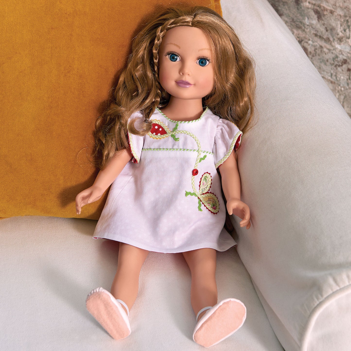 Example doll wearing a white dress with embroidery sitting on a surface.