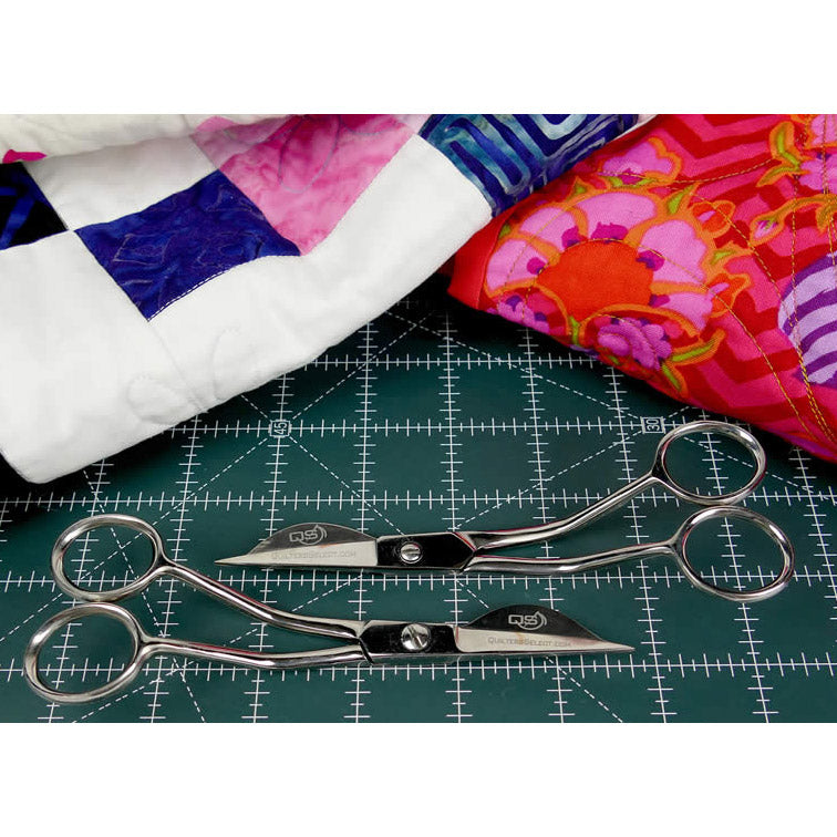 Select Wave Applique Scissors feature duckbill blades crafted from German grade steel for superior sharpness and durability. The photo shows the right-handed and left-handed scissors on a cutting mat. QSTOOL & QSTOOL1