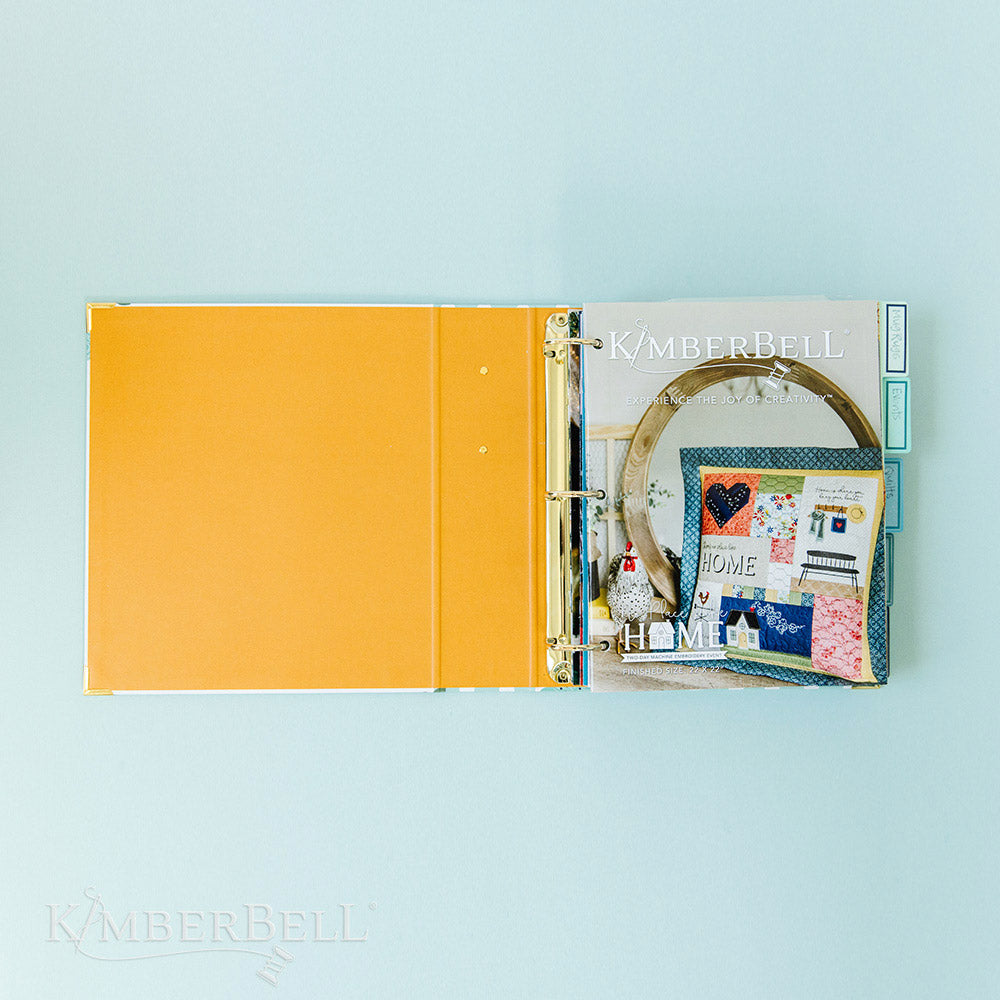 Inspire yourself with the Experience the Joy Binder (KDMR131) by Kimberbell. Each 3" binder includes 5 tab dividers and 2 sheets of stickers, plus gold metal corners to ensure the durability. This photo shows the inside cover, which is solid orange and a few instructions already in the binder.
