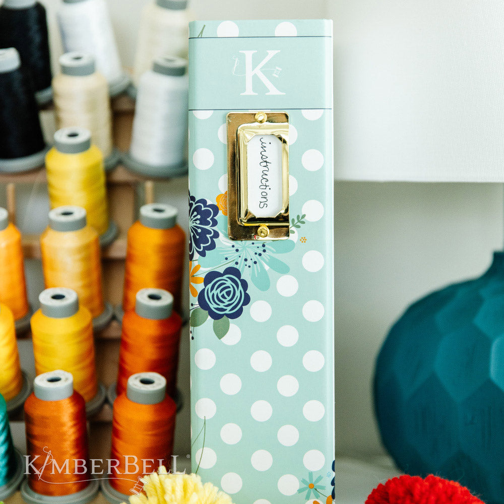 Inspire yourself with the Experience the Joy Binder (KDMR131) by Kimberbell. Each 3" binder includes 5 tab dividers and 2 sheets of stickers, plus gold metal corners to ensure the durability. This photo shows the side of the binder as it is standing on a bookshelf.