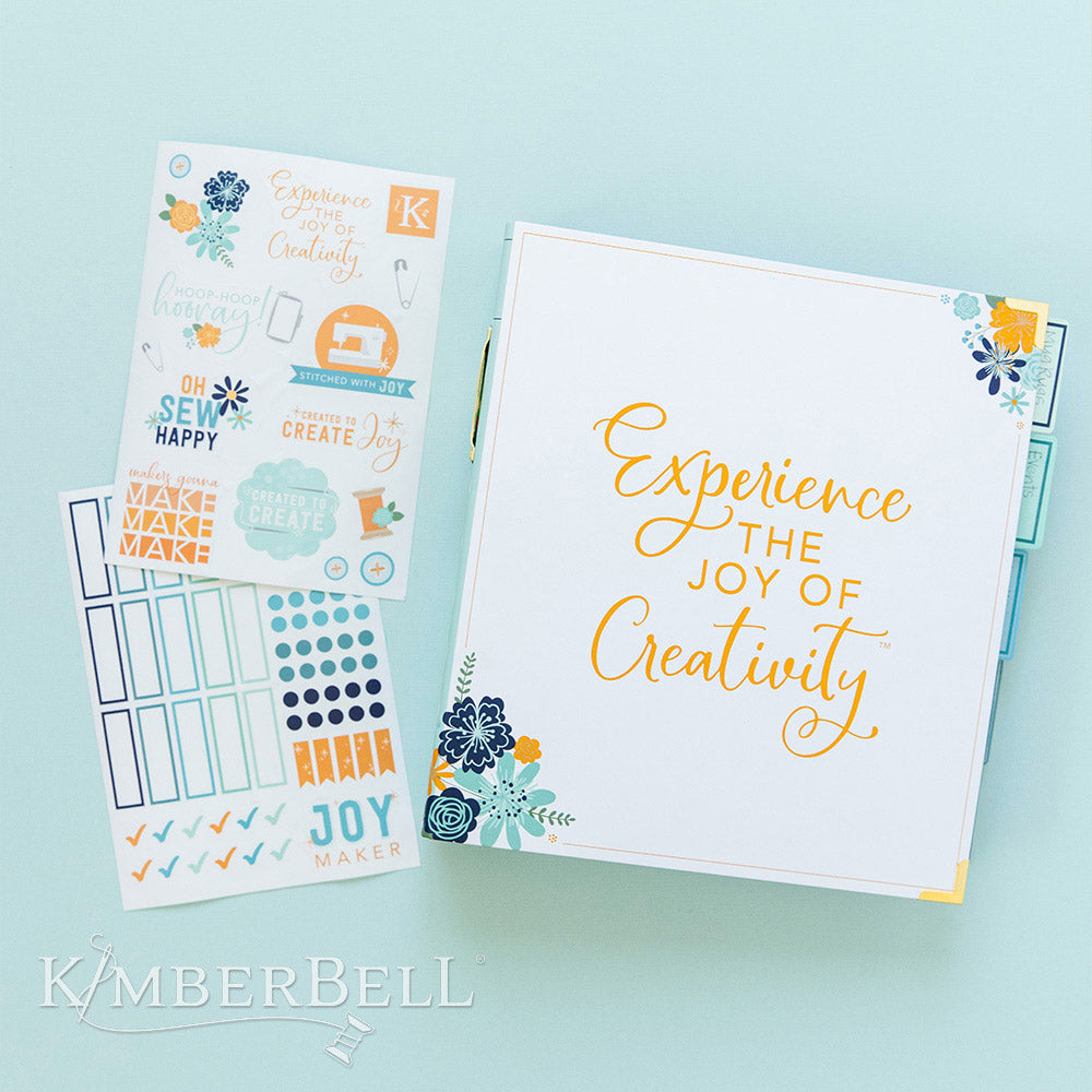 Inspire yourself with the Experience the Joy Binder (KDMR131) by Kimberbell. Each 3" binder includes 5 tab dividers and 2 sheets of stickers, plus gold metal corners to ensure the durability. This photo shows the front of the binder and the detail in the sticker pages.
