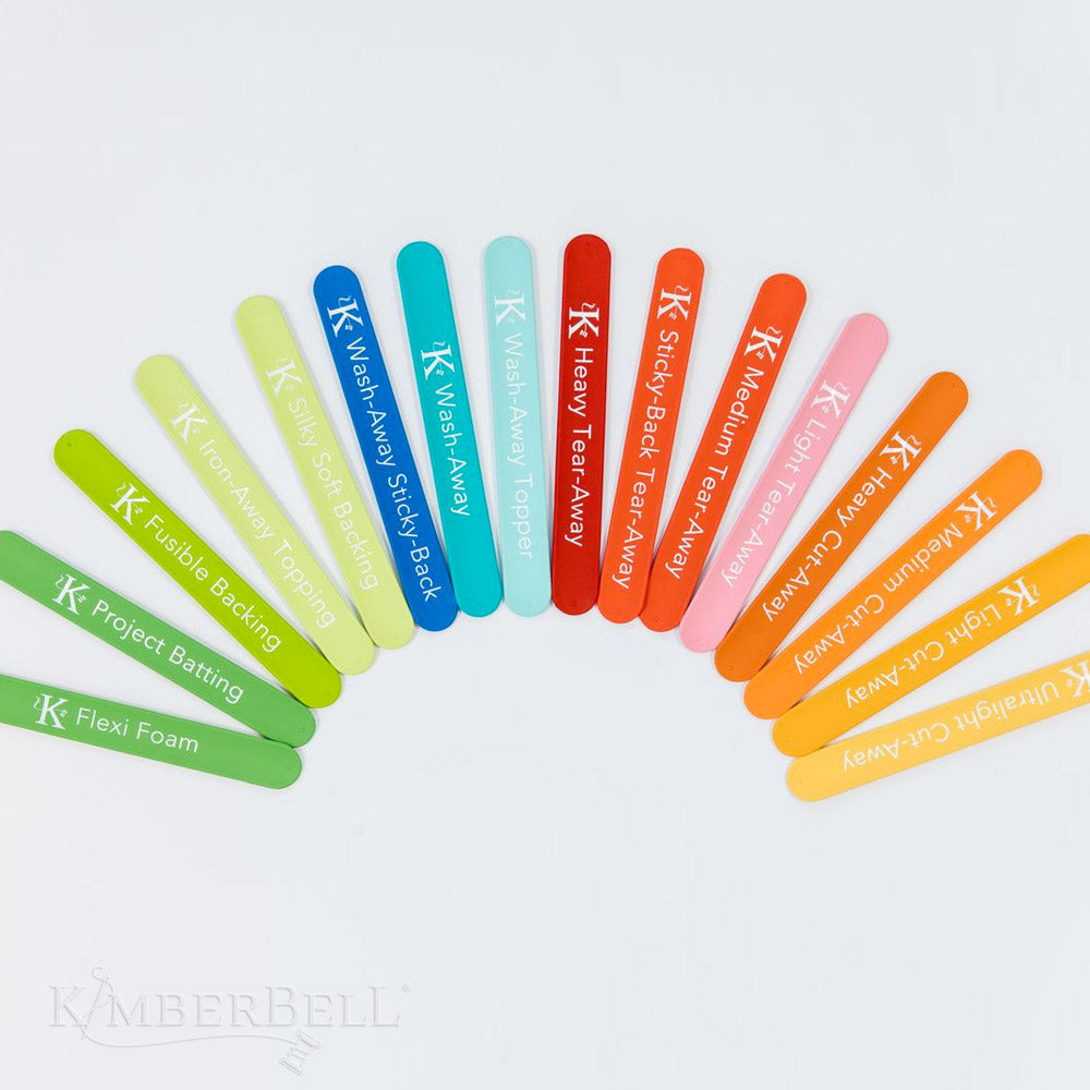 Stabilizer Slap Bands by Kimberbell (KDST141) features 16 stabilizer slap bands using Kimberbell’s color system of including Tear-Away in Red, Cut-Away in Orange, Wash-Away in Blue and Specialty products in Green. The packaging color for each type moves from lighter to darker as the weight of the stabilizer moves from lighter to heavier, making the perfect stabilizer easy to spot. This photo shows the 16 slap bands fanned out in their corresponding colors.