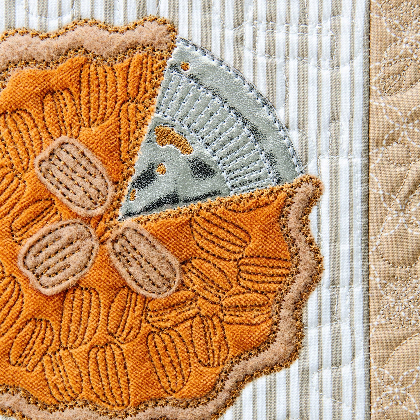 Kimberbell’s Sweet as Pie Bench Pillow KD5118 is a feast for the eyes! Create pie filling with fabric and iron-on vinyl, then top with a lattice crust, interchangeable ribbons, a cork rolling pin, and so much more to create a warm decor to be thankful for. The photo shows the detail of embroidery leather, pumpkin spice velveteen, gingerbread felt and pecan stitching detail.