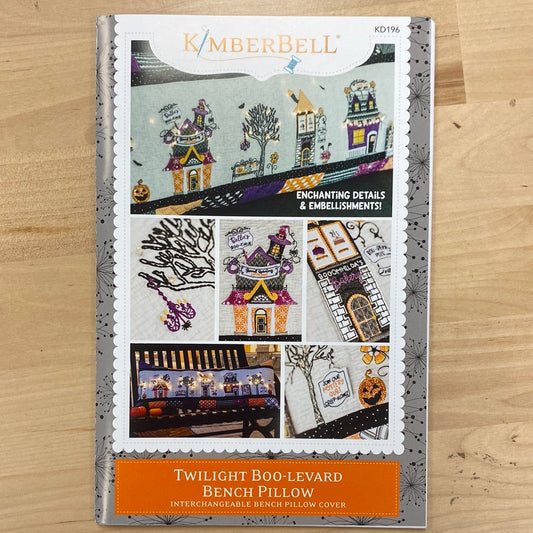 Treat yourself this Halloween with our Twilight Boo-levard Bench Pillow pattern (KD196) by Kimberbell! Featuring a spooky tree, embellished with lights, and designs from Candy Corn Quilt Shoppe and Broomhilda's Bakery. Photo shows product front.