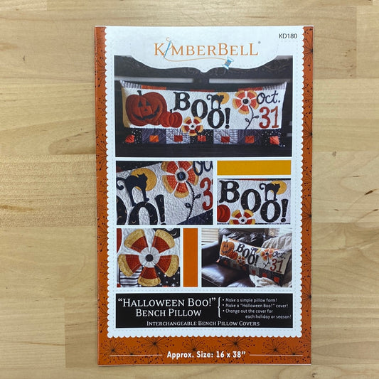 Unleash your Halloween spirit with the spook-tacular Halloween Boo! Bench Pillow Pattern for domestic sewing machine (KD180) by Kimberbell! Featuring a candy corn flower, black cat and fun "boo!" and "oct 31" wording, this applique pattern is perfect for any regular sewing machine. Photo shows the front of the package.