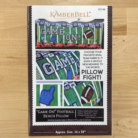 Unleash your inner sports enthusiast with the Game On! Bench Pillow Pattern (KD188) by Kimberbell. Show off your team pride with customizable borders and fun appliques including football, goal post, and game on wording. Perfect for any regular sewing machine. Photo shows product front.