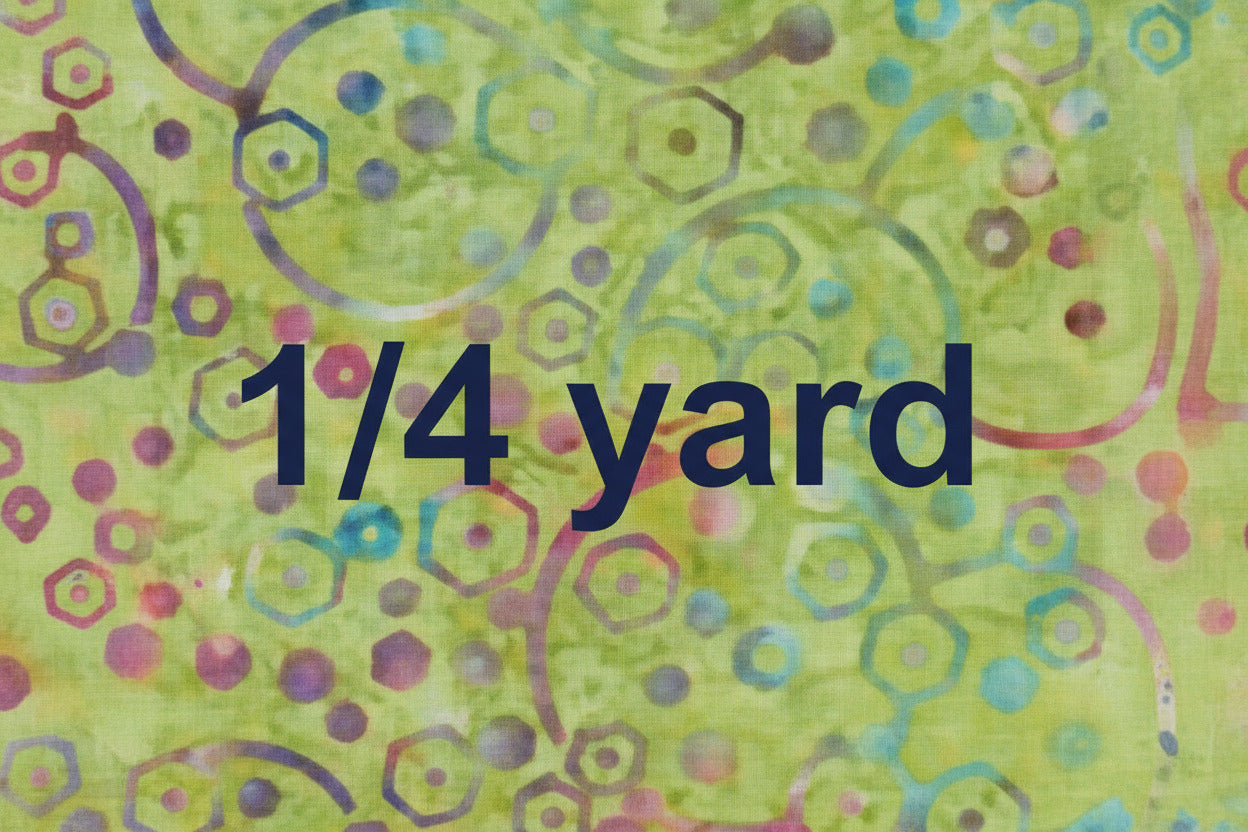 Batik fabric with a green background and multicolored circles, hexagons and dots with the words 1/4 yard