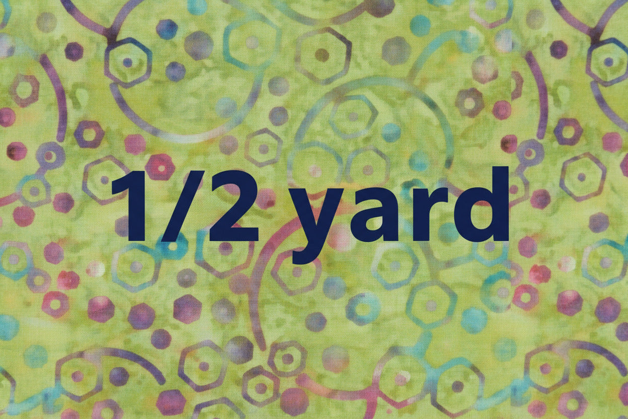 Batik with green background and multicolored circles, dots and hexagons with the words 1/2 yard