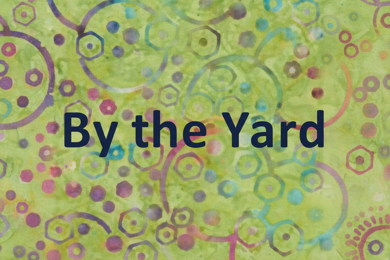 Green Backround batik with multicolored circles dots and hexagons with the words By the Yard.