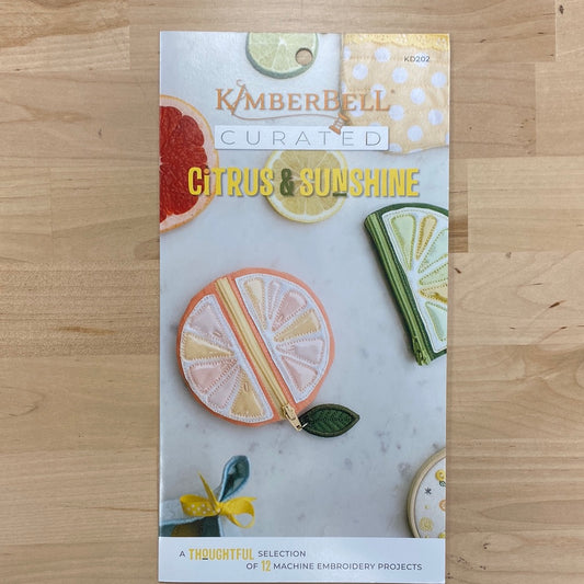 Bright, beautiful, and bursting with creativity, Kimberbell Curated: Citrus & Sunshine includes 12 fresh and fabulous machine embroidery projects. “Squeeze the Day” with a colorful tea towel, and “Be the Sunshine” with a pretty Pocket Tote! Photo shows product front.