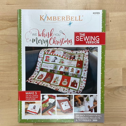 We “Whisk” You a Merry Christmas! (KD723) is Kimberbell’s feature quilt and holiday tribute to sweet Christmas confections and even sweeter traditions and memories. Dimensional elements include flexible foam whipped cream, marshmallow poms, a clear vinyl cake dome, applique glitter countertop mixers, and more! Photo shows product front cover.