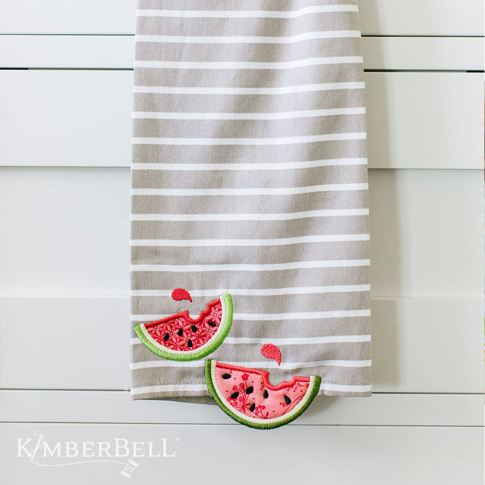 Kimberbell Over the Edge Applique for Spring and Summer (KD588) features 3D applique, plaques, and fun pockets. This photo shows a sample of a watermelon applique. Once watermelon slice is on the tea towel, and one if hanging off.