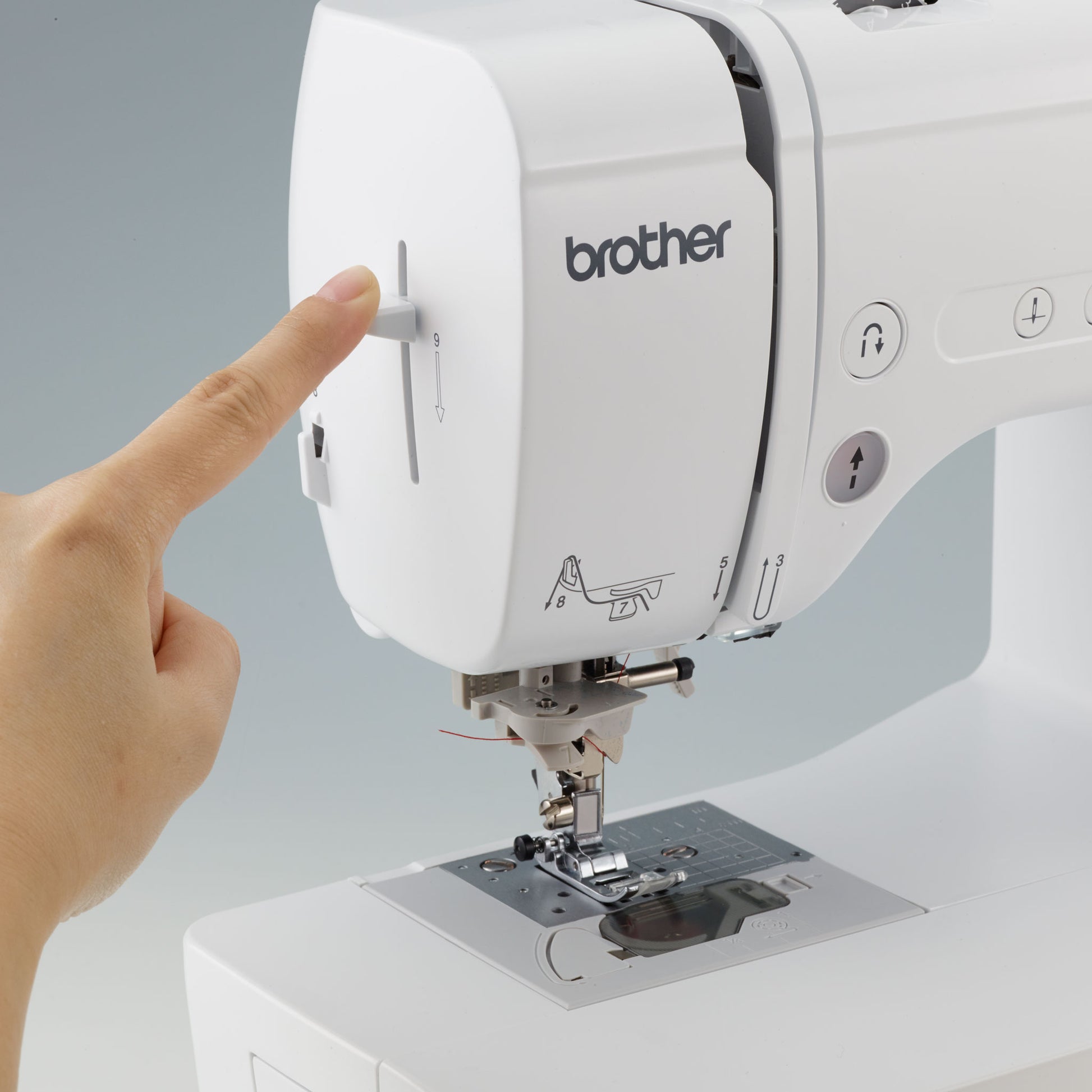 Brother NS1750D sewing machine with a hand pointing to a button on a light gray background, which is the automatic needle threader.