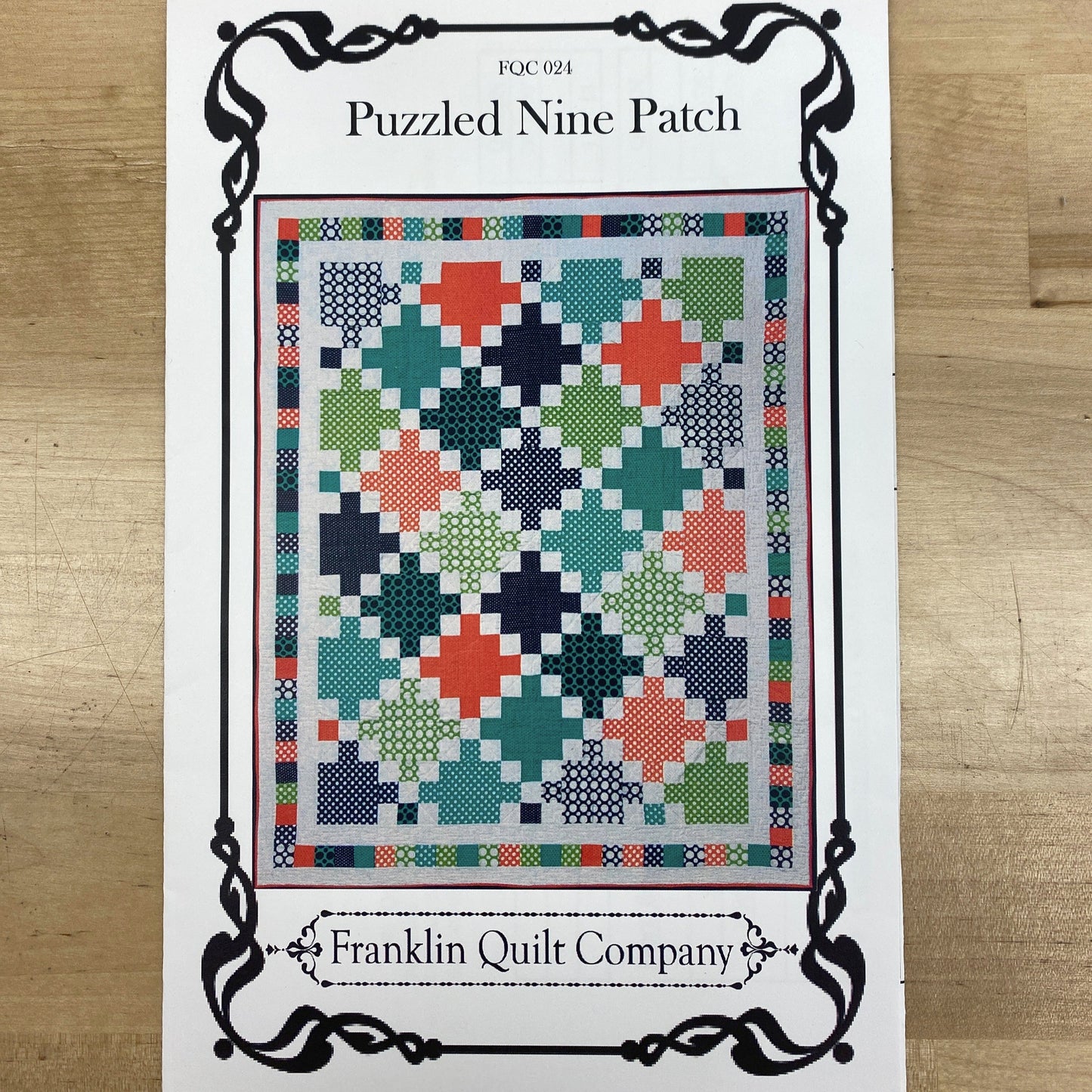 This quilt features alternating monochrome nine-patch blocks with Irish Chain blocks to create a quilt that looks like it is set on-point, bu really only has horizontal seams. it is finished by a simple pieced border, and the pattern includes instructions for multiple sizes. The photo shows the front cover of the pattern with a picture of the finished quilt.