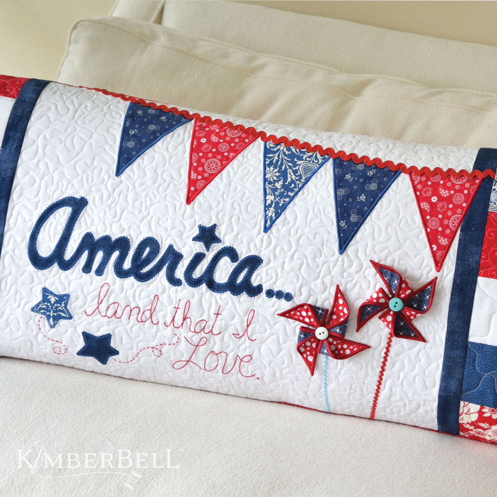 Celebrate freedom with the America, Land That I Love Bench Pillow pattern (KD523) for machine embroidery by Kimberbell! Like a hometown parade, the America, Land That I Love Bench Pillow features a pennant banner, dimensional pinwheels, America applique and scrappy borders in shades of red, white and blue.