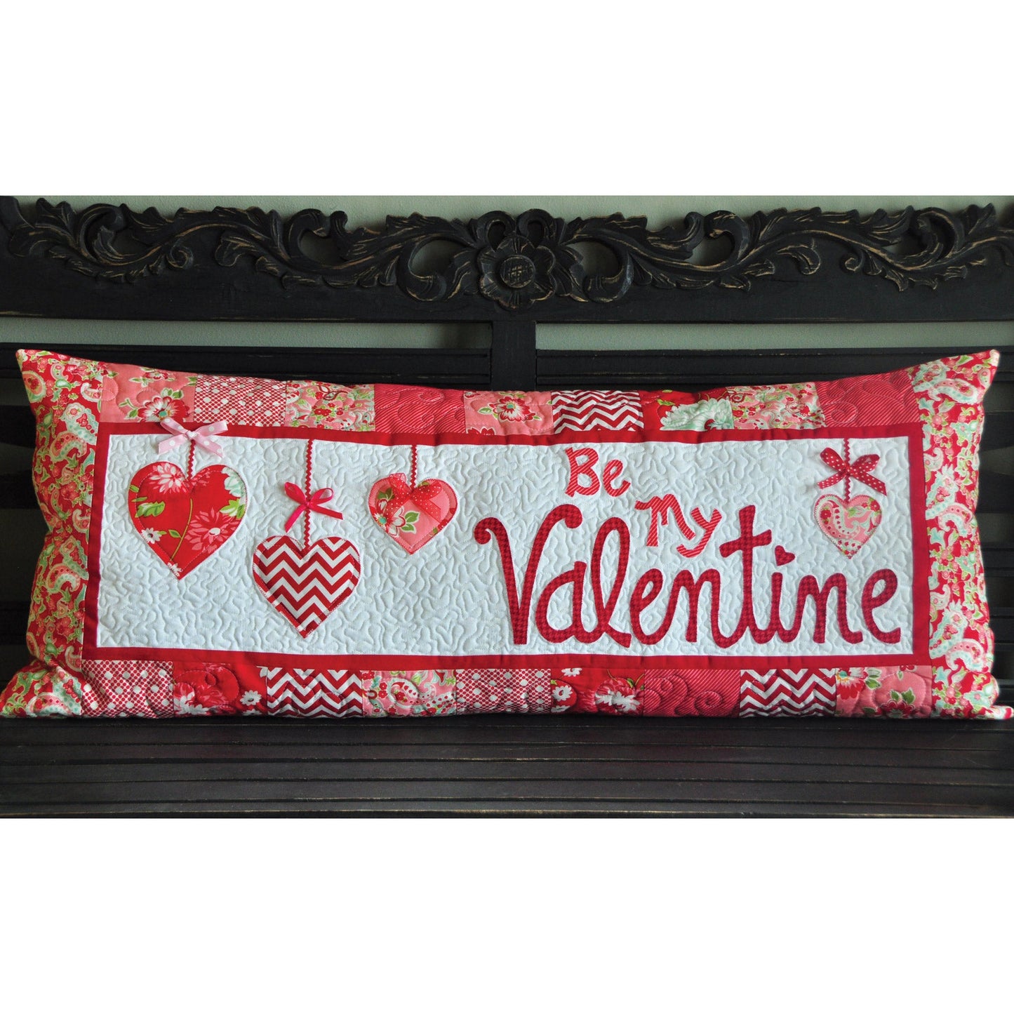 Dangling hearts, a sweet sentiment, and pieced border are somethings to love about the Be My Valentine Bench Pillow Sewing Version (KD166) by Kimberbell. It is the perfect way to bring in the season and announce your love to someone special. Photo shows the finished pillow cover.