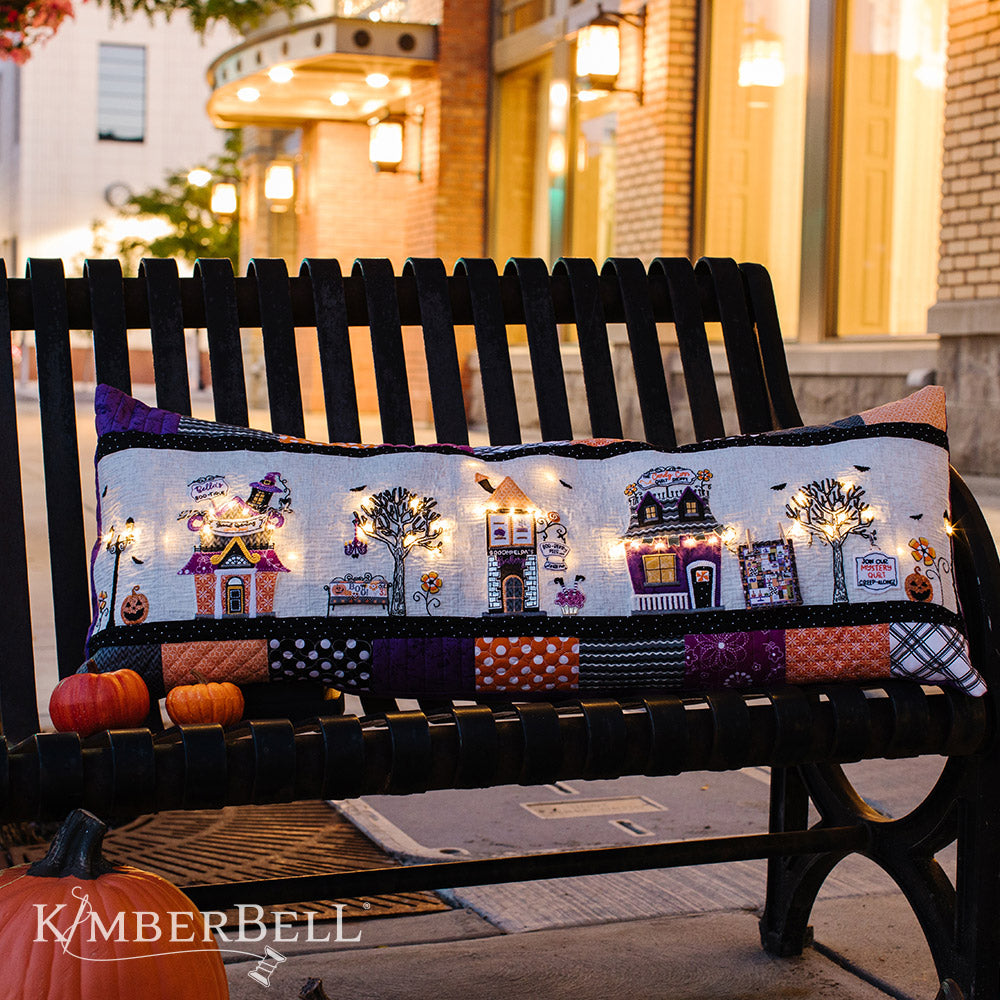 Take a stroll along Twilight Boo-levard (KD594) to visit all of your favorite haunts with this machine embroidery bench pillow pattern by Kimberbell.  With fairy lights, embroidery leather, buttons and mylar and more, the Twilight Boo-levard Bench Pillow is so enchanting, it’s almost scary!