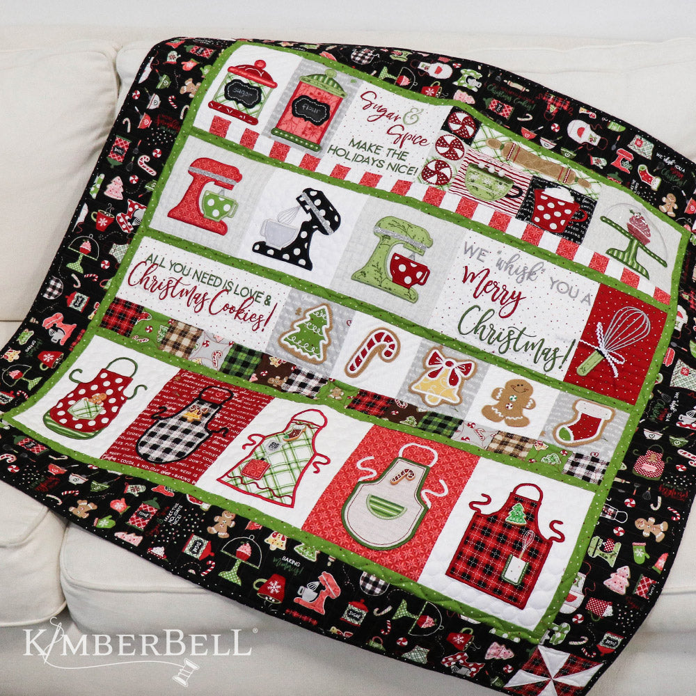 We “Whisk” You a Merry Christmas (KD806) is Kimberbell’s feature quilt and holiday tribute to sweet Christmas confections and even sweeter traditions and memories. Dimensional elements include flexible foam whipped cream, marshmallow poms, a clear vinyl cake dome, applique glitter countertop mixers, and more! Picture shows sample quilt.