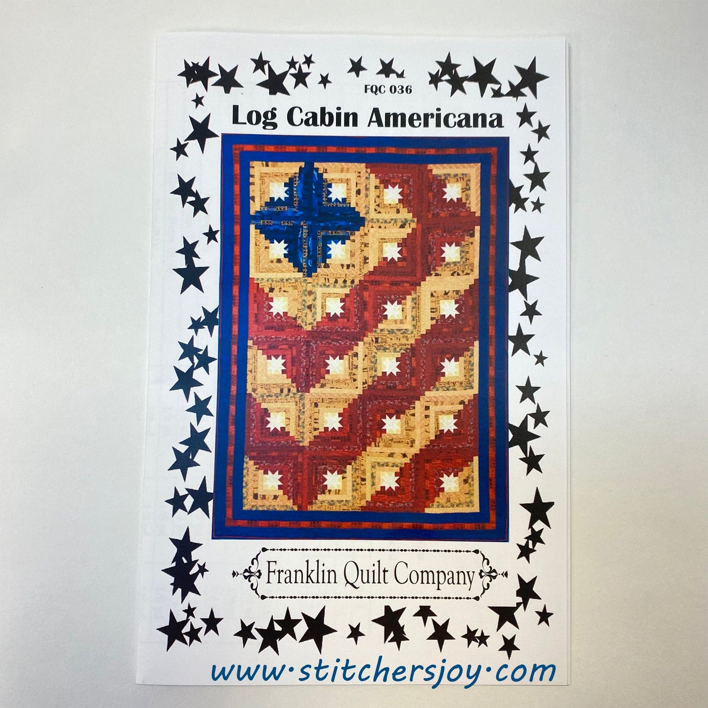 Log Cabin Americana quilt pattern front cover by Franklin Quilt Company features a red, white, blue, and cream colored quilt made of log cabin blocks built around a white center star. The setting is a barn-raising pattern with four blue/cream cabin blocks surrounded by red/cream cabin blocks to create stripes across the quilt. The pattern in the colorway would be perfect for a patriotic quilt or Quilts of Valor, or the colors are easily changed to any color scheme for the star in your life.